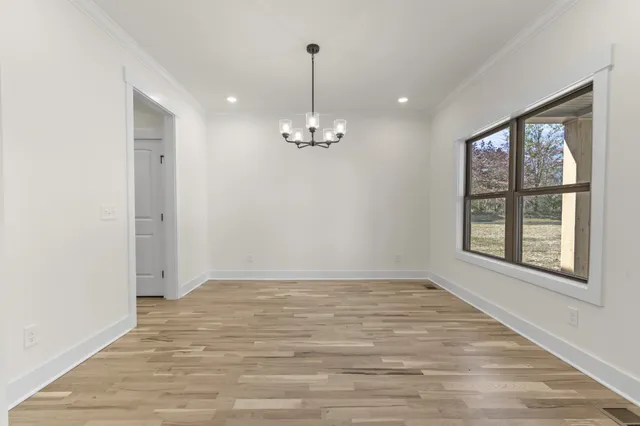 a view of an empty room with window and wooden floor