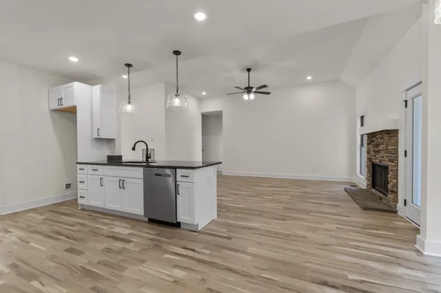 a large white kitchen with a refrigerator a sink dishwasher a fireplace and a dining table with wooden floor