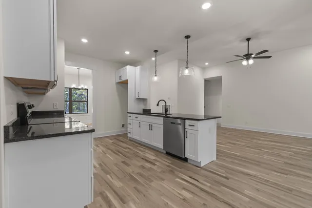 a large kitchen with granite countertop a large counter top a sink stainless steel appliances and cabinets