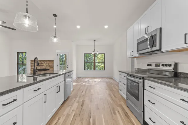 a large kitchen with stainless steel appliances granite countertop a lot of counter space and wooden floors