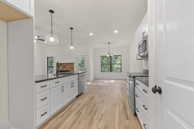a large kitchen with granite countertop a stove a sink and a refrigerator