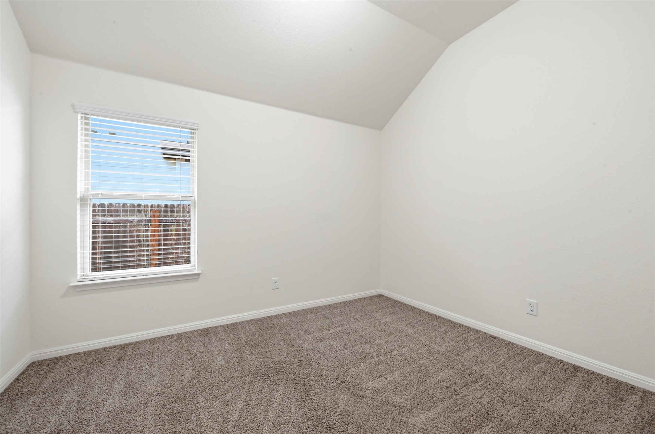 13116 Alans Way Manchaca, TX 78652 - Photo 20 of 25 Room featuring a window with blinds, vaulted ceiling, light-colored walls, and textured carpet flooring