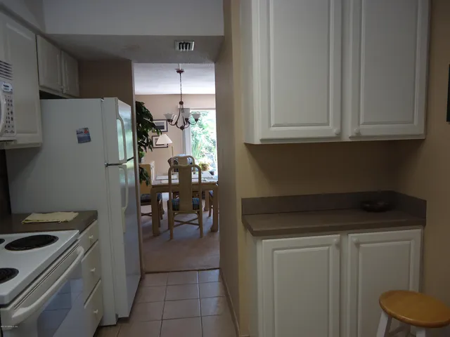 a kitchen with a refrigerator and white cabinets
