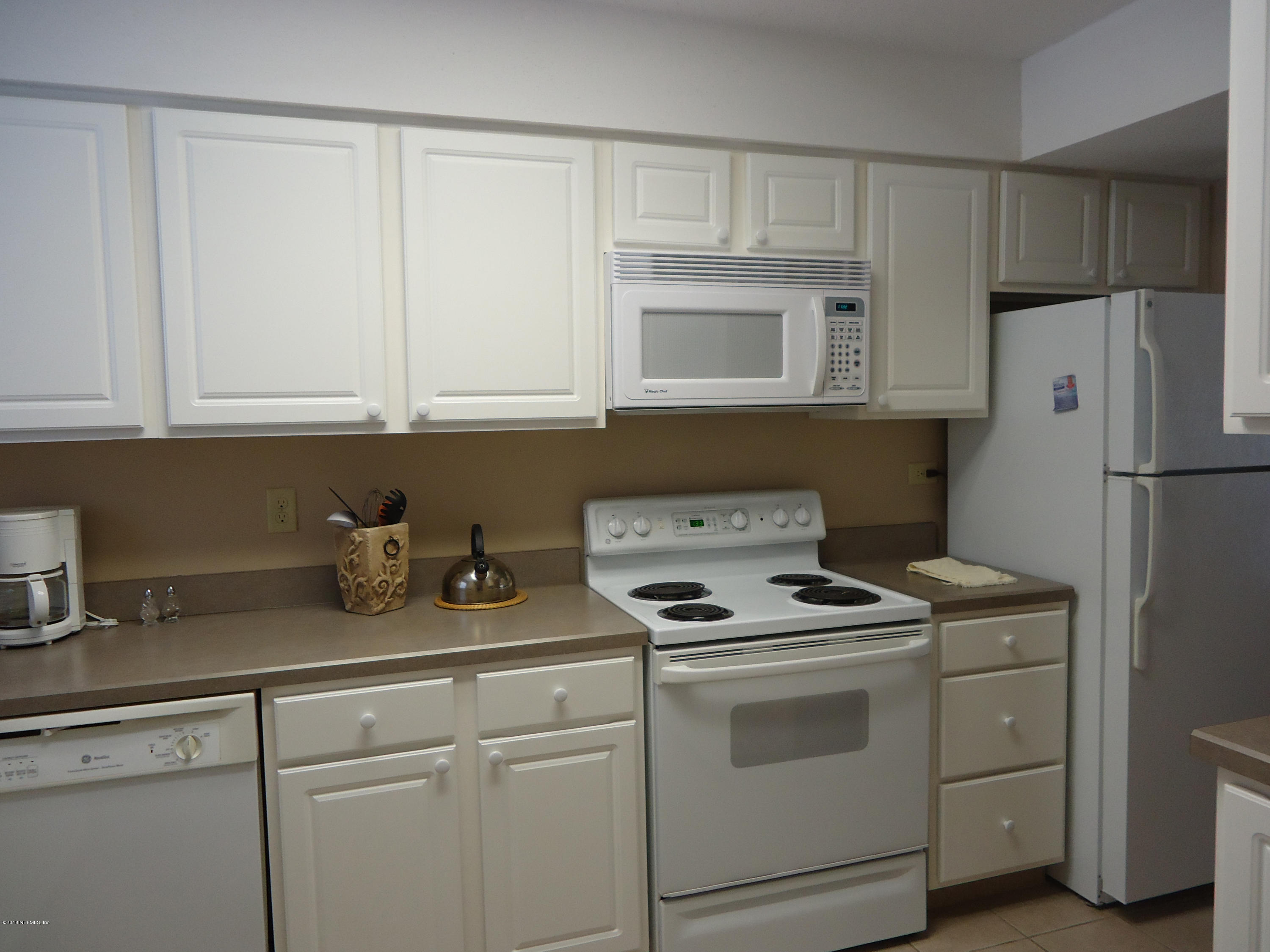 2233 Seminole Road, Unit 39 Atlantic Beach, FL 32233 - Photo 7 of 18 a kitchen with granite countertop white cabinets and refrigerator