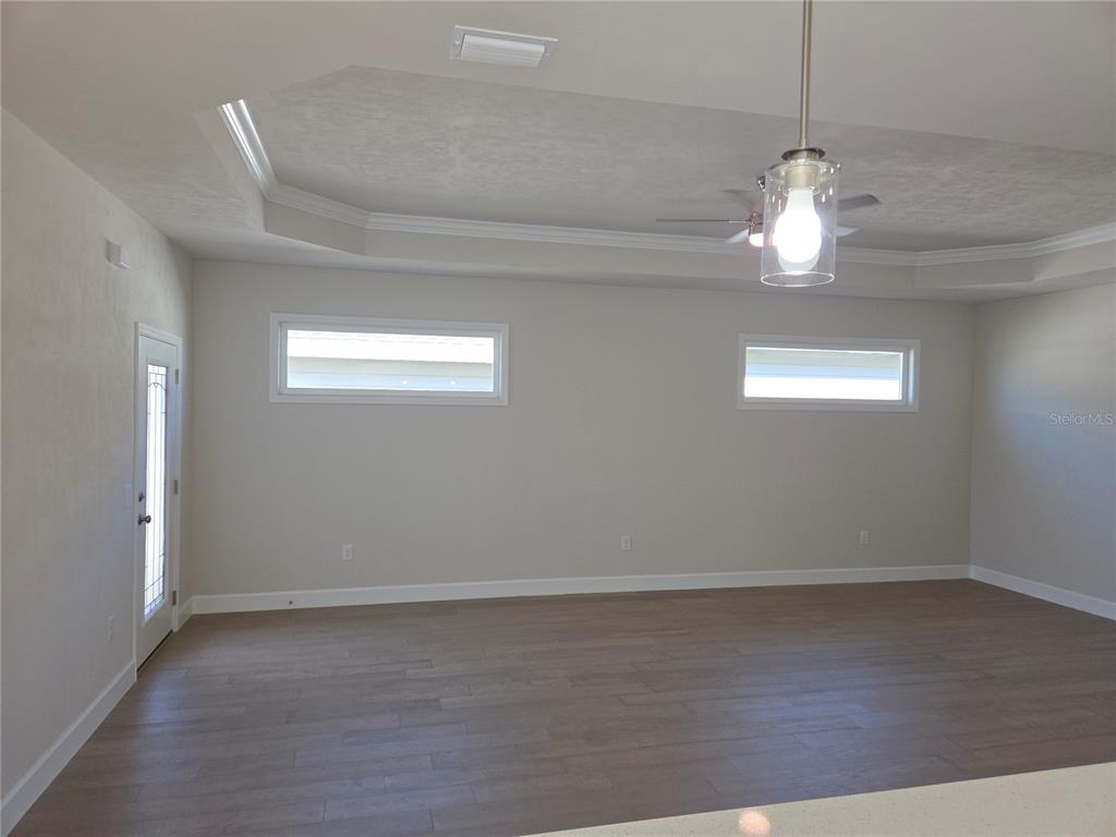 1761 Southwest 244th Way Newberry, FL 32669 - Photo 8 of 21 an empty room with wooden floor chandelier fan and windows