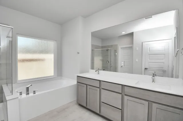 a bathroom with a double vanity sink mirror and bathtub