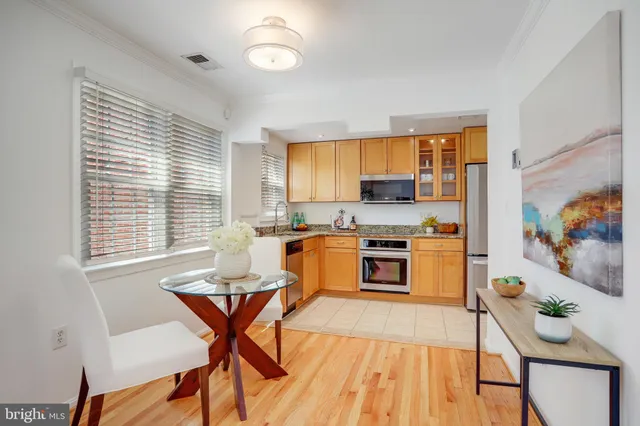 a kitchen with stainless steel appliances granite countertop a stove top oven a sink a dining table and chairs with wooden floor