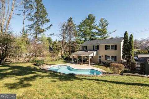 a view of house with swimming pool and trees in the background