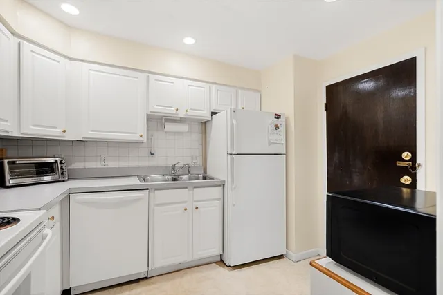 a kitchen with white cabinets and refrigerator
