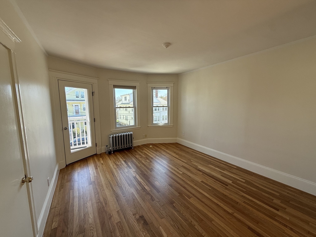 15 Chauncey Street, Unit 2 Watertown, MA 02472 - Photo 2 of 16 a view of an empty room with wooden floor and window