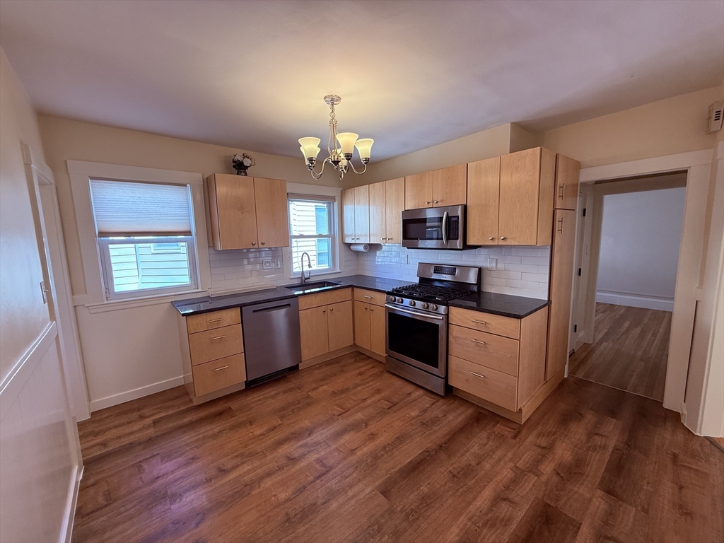 15 Chauncey Street, Unit 2 Watertown, MA 02472 - Photo 6 of 16 a kitchen with granite countertop wooden floors stainless steel appliances a sink and a window