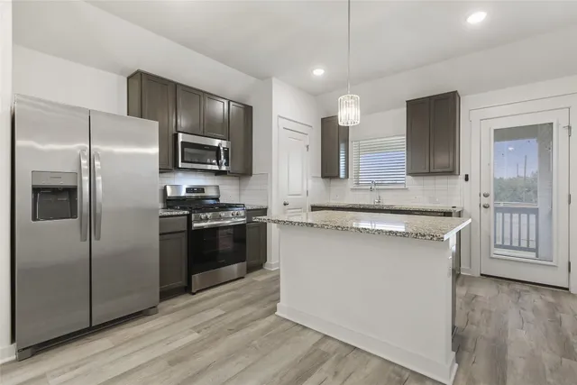 a kitchen with stainless steel appliances kitchen island granite countertop a refrigerator and a stove top oven