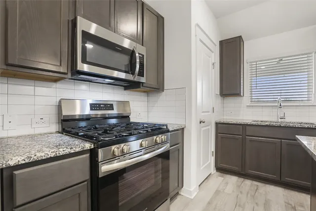 a kitchen with stainless steel appliances granite countertop a stove microwave and sink