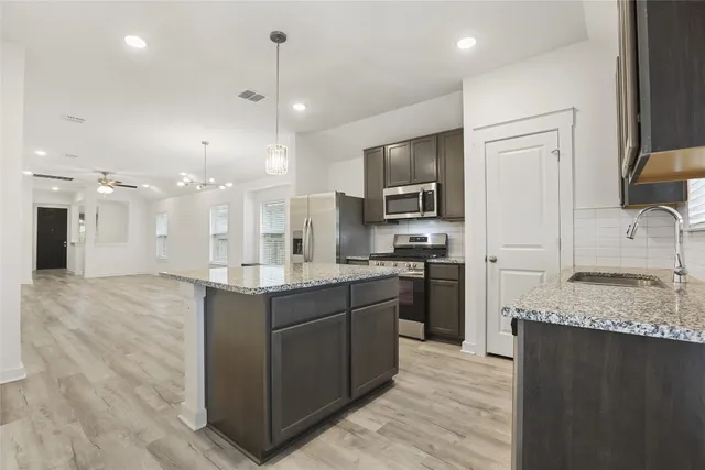 a large kitchen with stainless steel appliances kitchen island granite countertop a sink counter space cabinets and a refrigerator