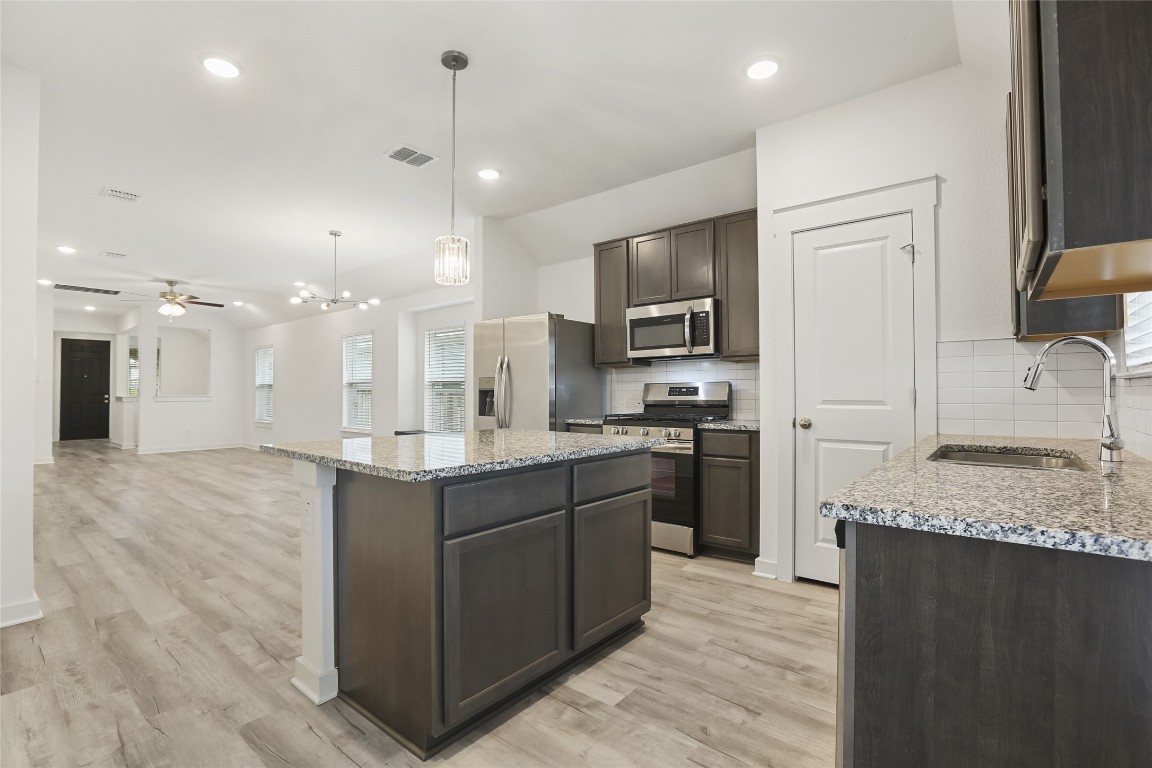 2340 Sawdust Drive Georgetown, TX 78633 - Photo 4 of 40 a large kitchen with stainless steel appliances kitchen island granite countertop a sink counter space cabinets and a refrigerator