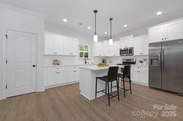 a kitchen with kitchen island white cabinets and stainless steel appliances