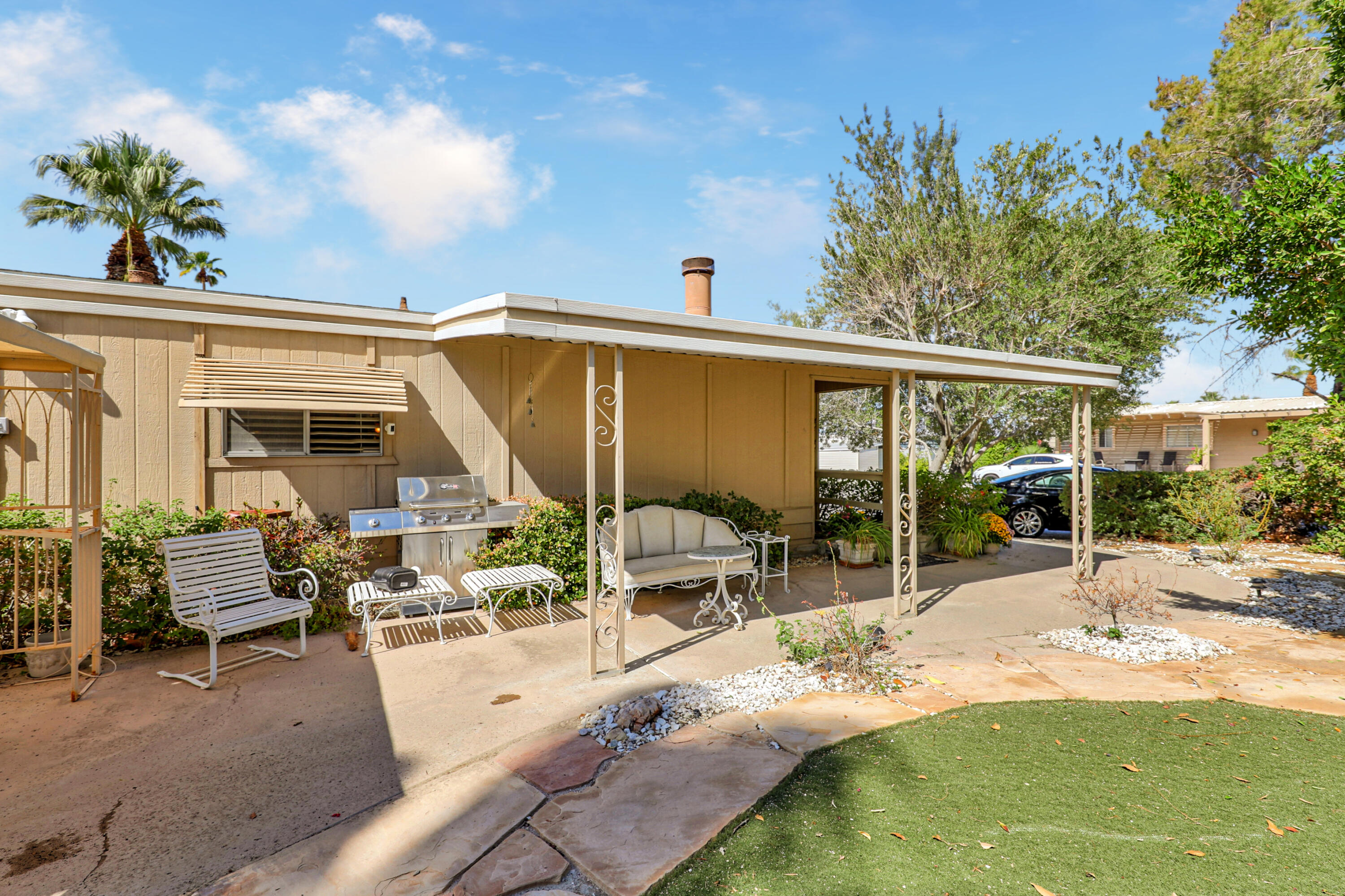 49305 Highway 74, Unit 86 Palm Desert, CA 92260 - Photo 3 of 31 a view of a patio with table and chairs potted plants and large tree