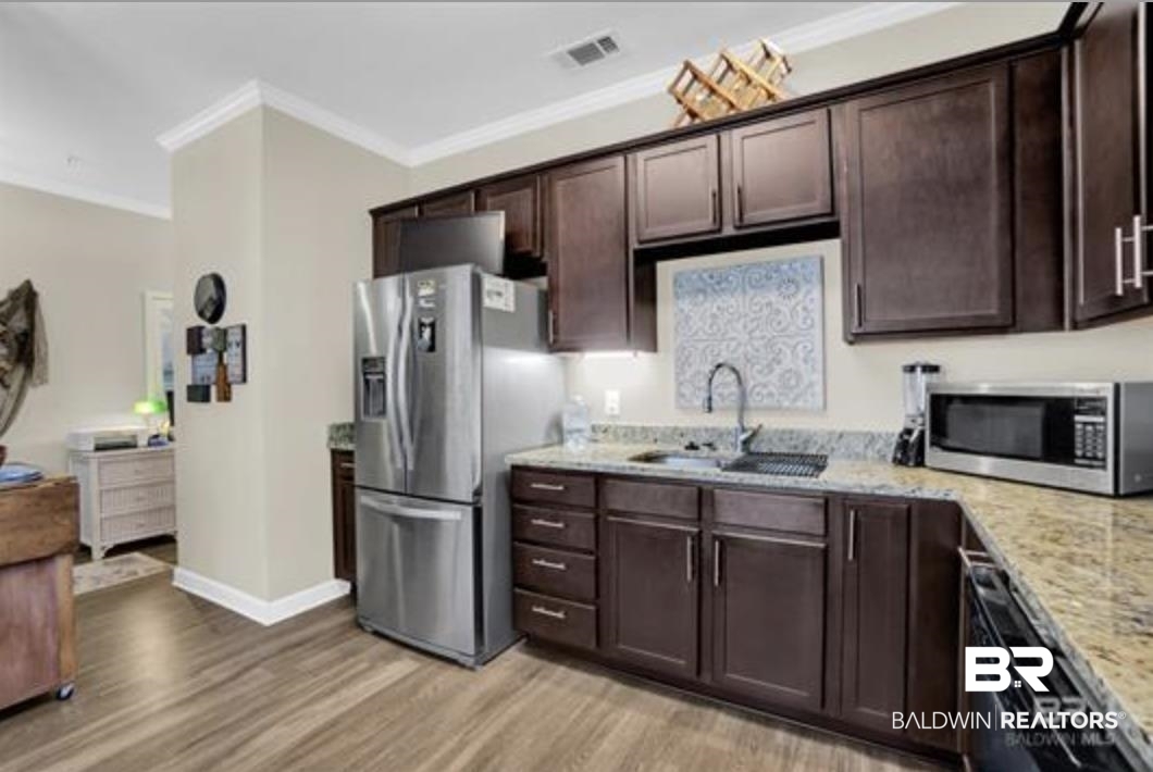 430 West Fort Morgan Road Gulf Shores, AL 36542 - Photo 22 of 27 Kitchen featuring dark wood cabinetry, granite-finish countertops, stainless steel appliances, and wood-finish flooring