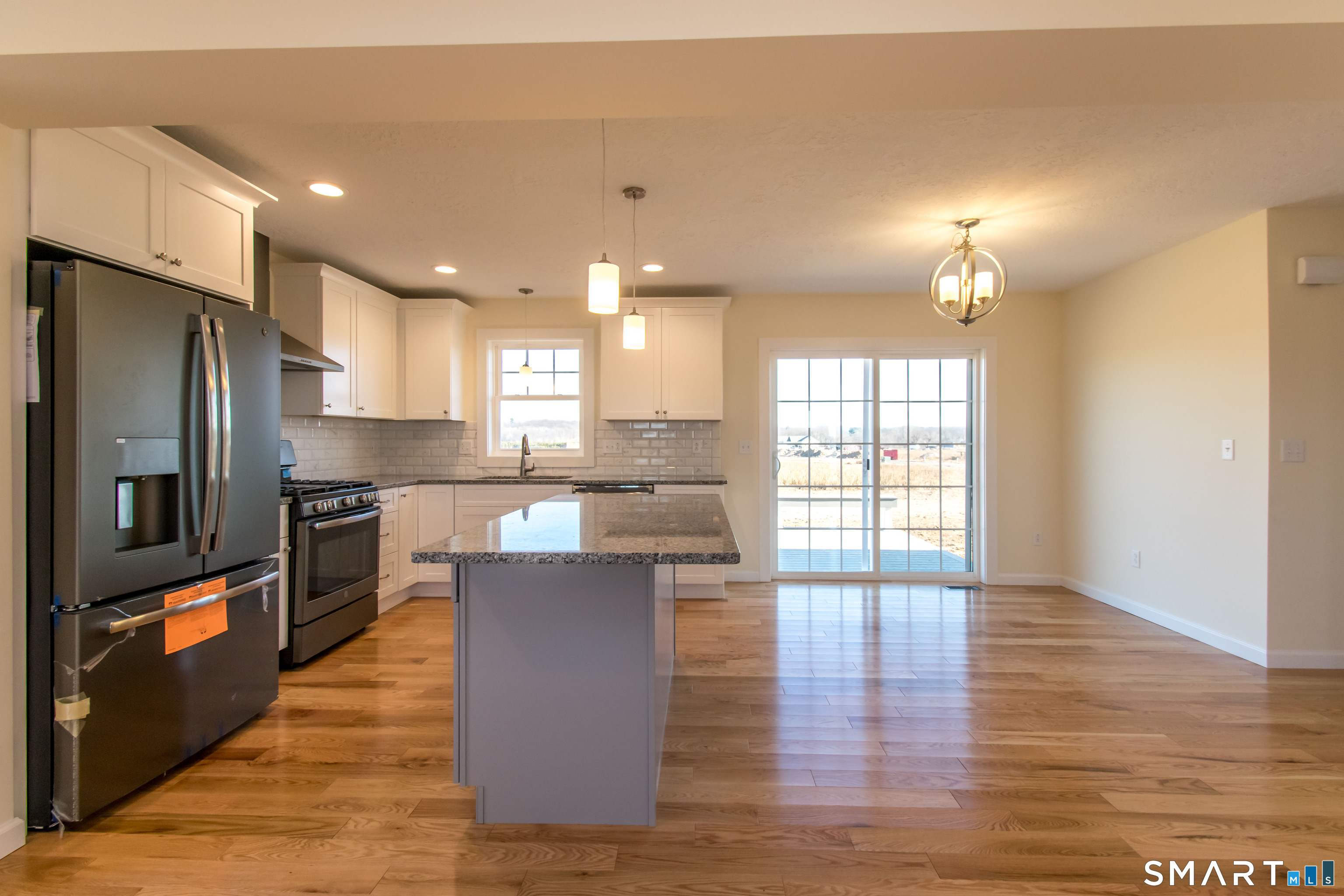 318 Capen Street Windsor, CT 06095 - Photo 17 of 30 a kitchen with stainless steel appliances granite countertop a refrigerator a sink dishwasher a stove and a dining table with wooden floor