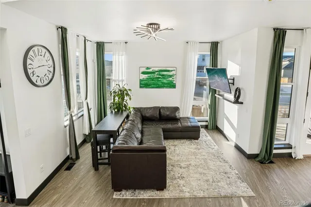 a living room with furniture a clock and a large window
