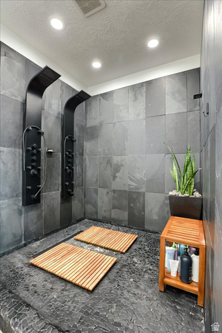 828 South Deer Road Tooele, UT 84074 - Photo 50 of 51 Spacious walk-in shower featuring dual matte black shower panels, pebble stone flooring, and large format wall tiling