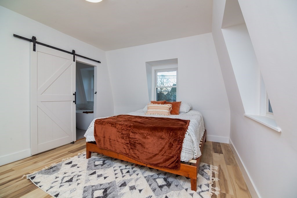 84 Dudley Street Medford, MA 02155 - Photo 25 of 27 a bedroom with a bed and wooden floor