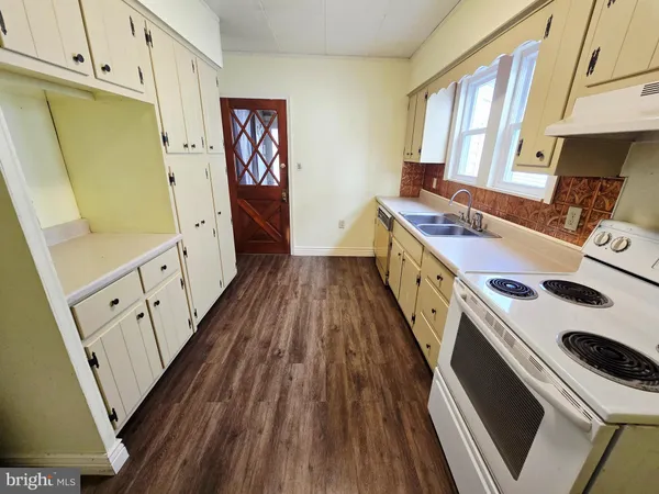 a kitchen with sink a refrigerator and wooden floor