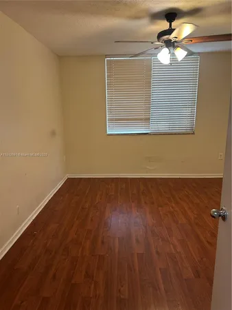 a view of a room with wooden floor and a ceiling fan