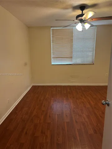 a view of a room with wooden floor and a ceiling fan