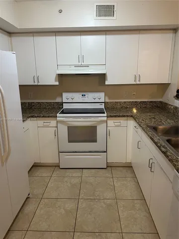 a kitchen with granite countertop white cabinets and white appliances