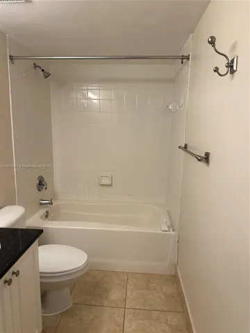 a bathroom with a granite countertop bathtub shower sink vanity and toilet