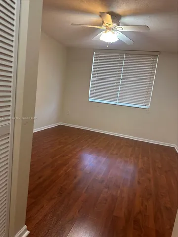 an empty room with wooden floor chandelier fan and windows