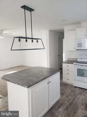 a kitchen with kitchen island a sink a stove and white cabinets