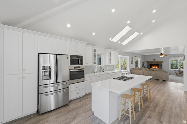 5788 Walden Ridge Drive Murray, UT 84123 - Photo 5 of 29 Modern kitchen featuring white cabinetry, stainless steel appliances, a center island with a cooktop, and wood-finish flooring