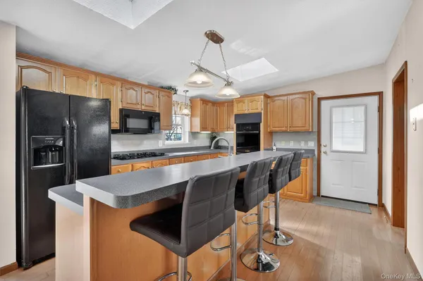 a kitchen with stainless steel appliances granite countertop a refrigerator a stove a sink a center island a dining table and chairs with wooden floor