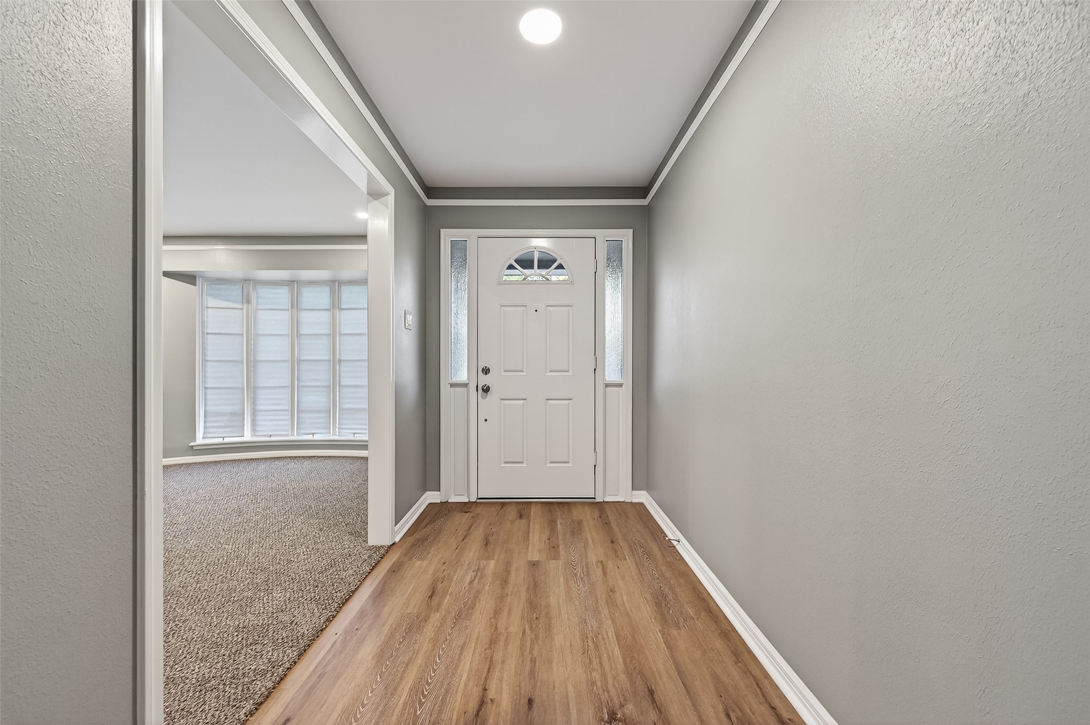902 Kingsbridge Road Houston, TX 77073 - Photo 14 of 43 The front door entry welcomes you with seamless wood-look flooring and a contemporary grey color palette, accented by crisp white crown molding and baseboards. The white entry door is framed by decorative sidelights and a semi-circle transom window, while the wide opening to the left leads into the carpeted living area.