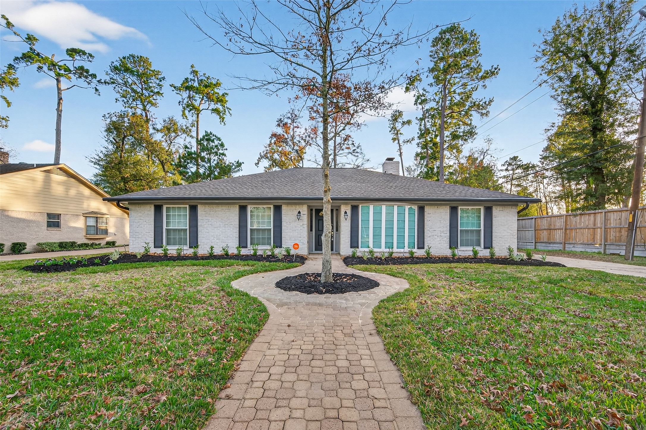 902 Kingsbridge Road Houston, TX 77073 - Photo 2 of 43 The property boasts a unique, curved paver walkway leading to the entrance, centered around a mature ornamental tree with a fresh mulch bed.