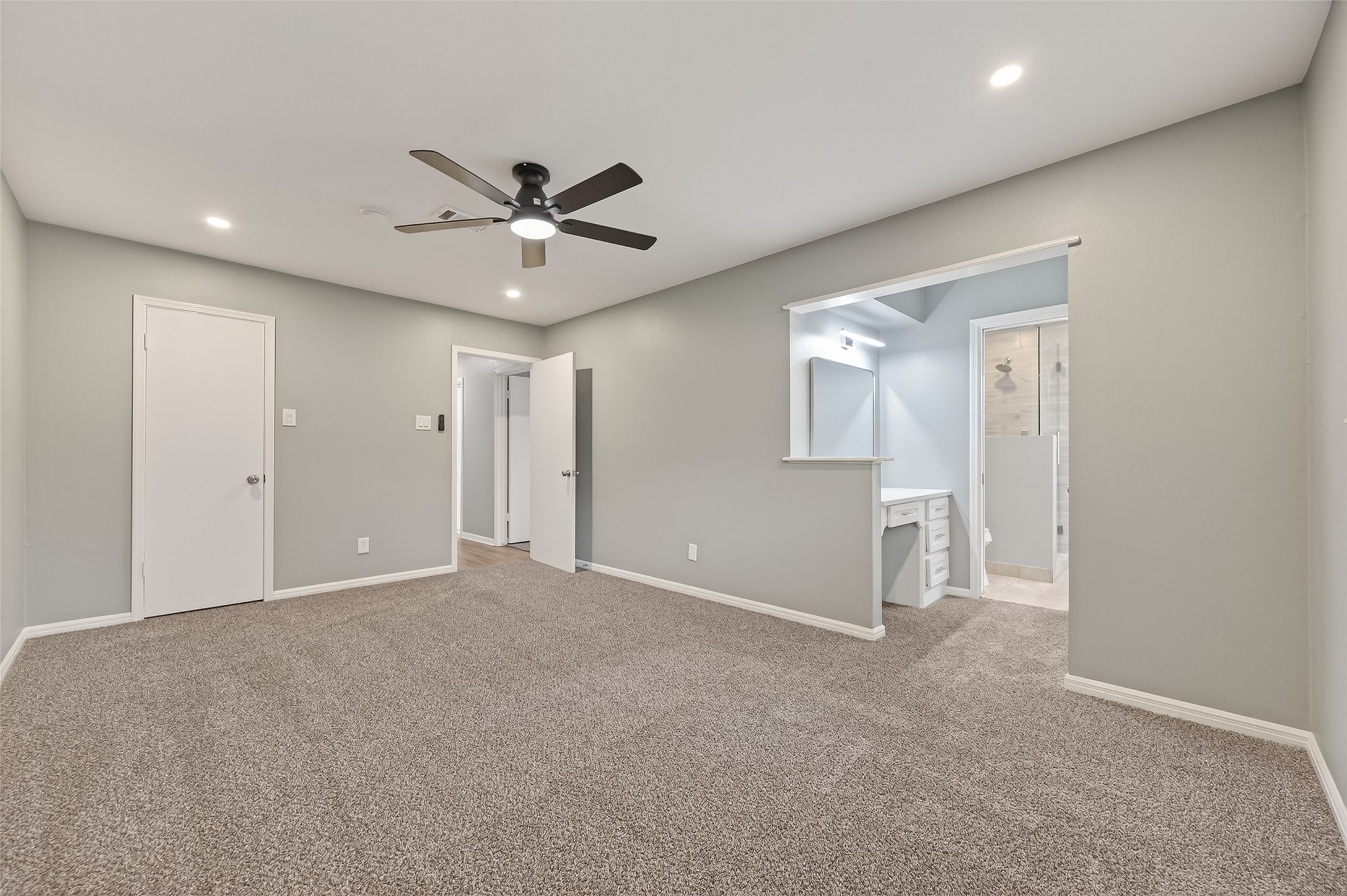 902 Kingsbridge Road Houston, TX 77073 - Photo 30 of 43 The spacious primary bedroom serves as a cozy retreat, featuring plush neutral carpeting and a window that fills the room with natural light. The space offers seamless access to the private ensuite bathroom, providing a perfect blend of comfort and convenience.