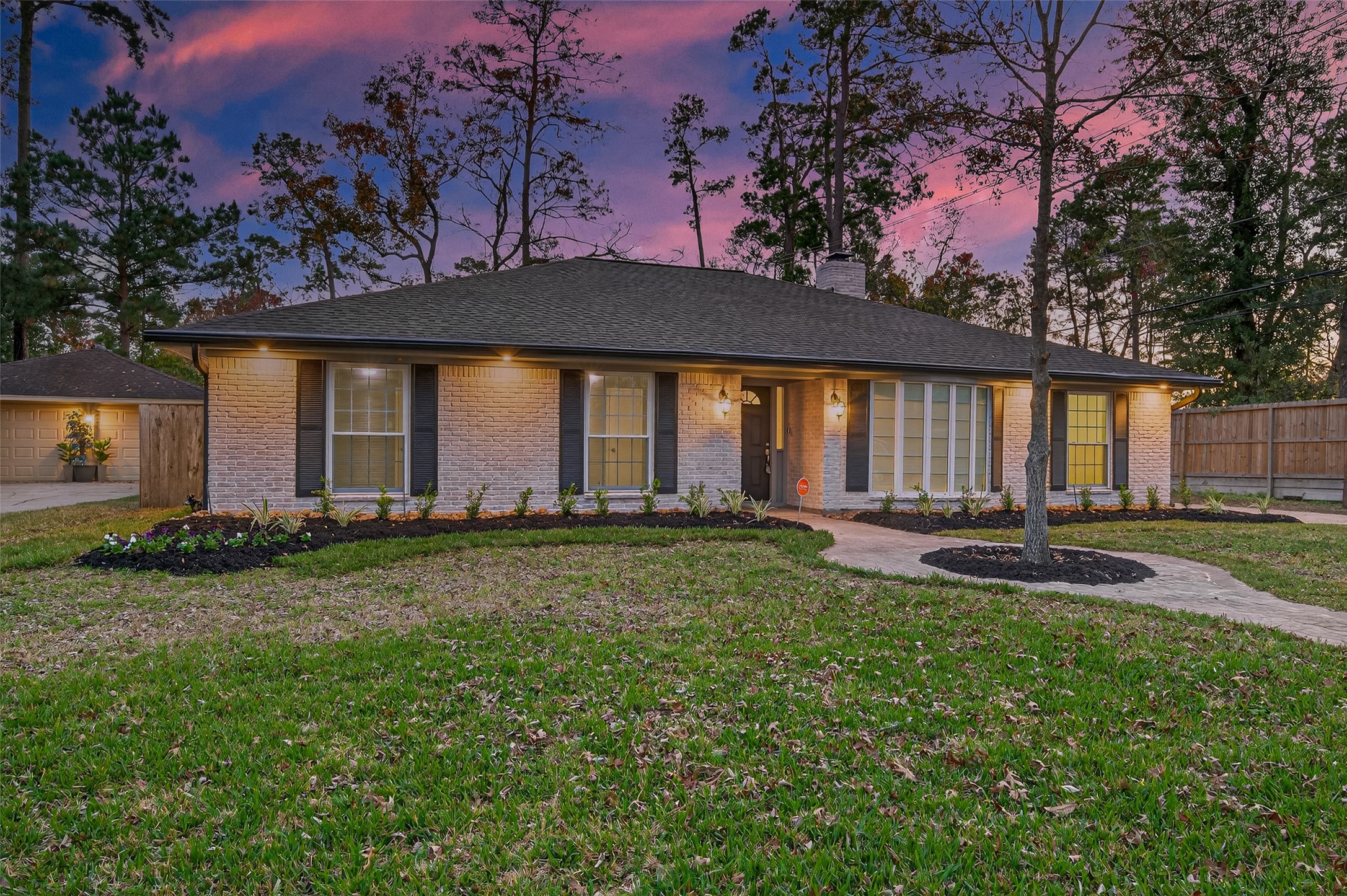 902 Kingsbridge Road Houston, TX 77073 - Photo 3 of 43 These shots capture the home’s stunning curb appeal during the "golden hour." Warm exterior soffit lighting and traditional wall sconces illuminate the brickwork against a vibrant sunset sky, highlighting the professional landscaping and the expansive front lawn.