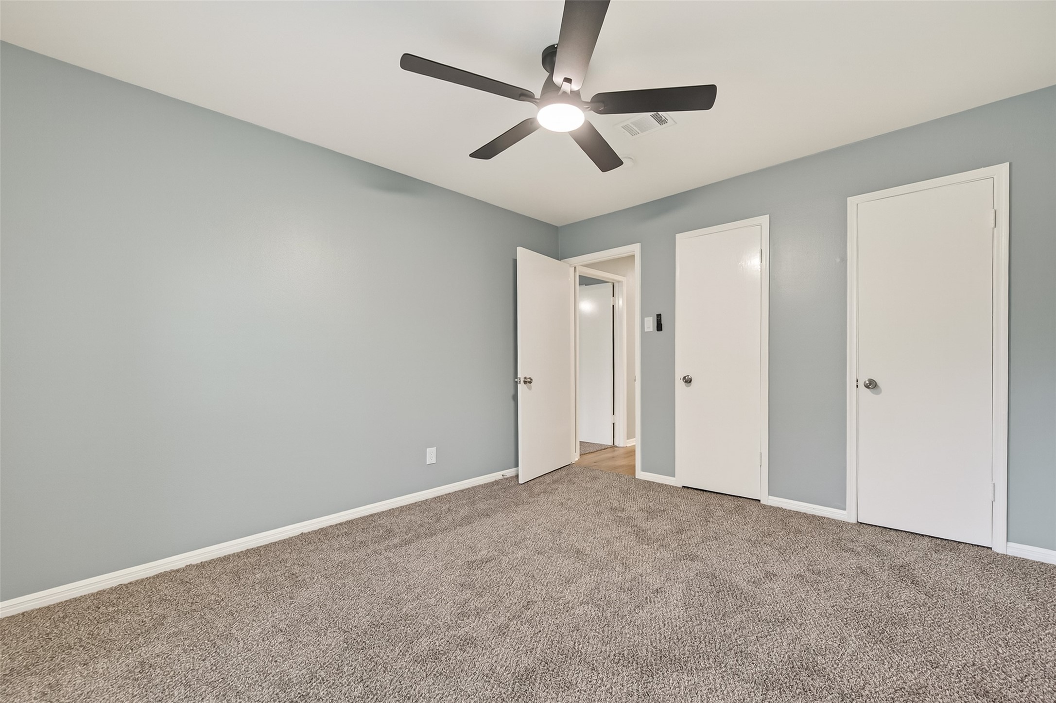 902 Kingsbridge Road Houston, TX 77073 - Photo 38 of 43 Bedroom 2 is equipped with dual closets, featuring classic white doors that blend seamlessly with the room's modern grey walls. These side-by-side storage spaces are conveniently located near the entry door, maximizing the room's functional layout.
