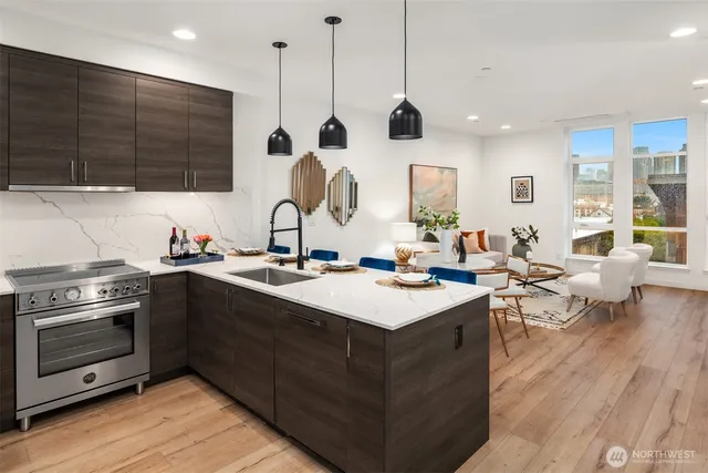 a kitchen with a stove a sink a counter space and a living room view