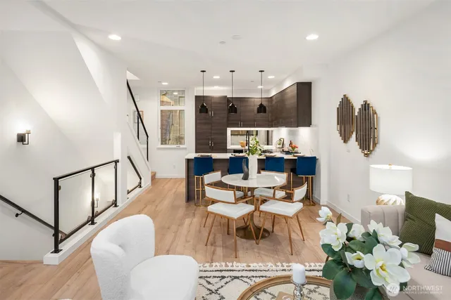 a living room with furniture kitchen view and a wooden floor