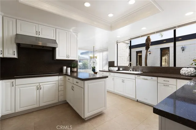a kitchen with granite countertop a sink and white cabinets