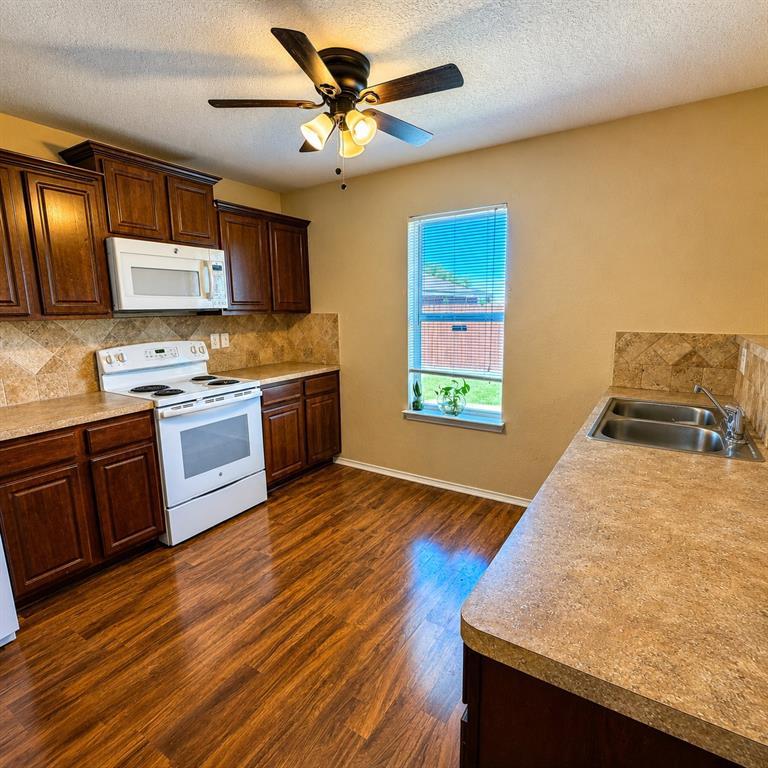 2003 Firefly Circle Waco, TX 76705 - Photo 2 of 29 Kitchen featuring wood-finish flooring, dark wood cabinetry, and speckled countertops