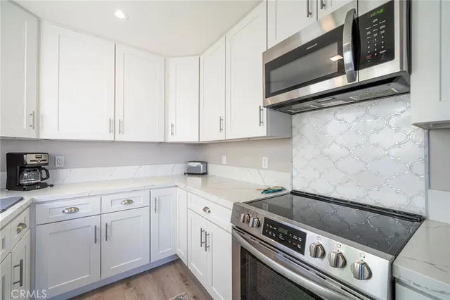 a kitchen with stainless steel appliances granite countertop white cabinets a sink a stove and dishwasher