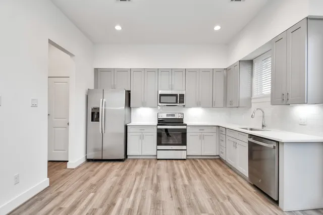 a kitchen with a sink cabinets stainless steel appliances and wooden floor