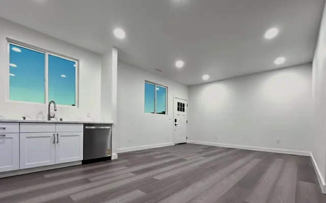 a view of a big room with wooden floor and windows
