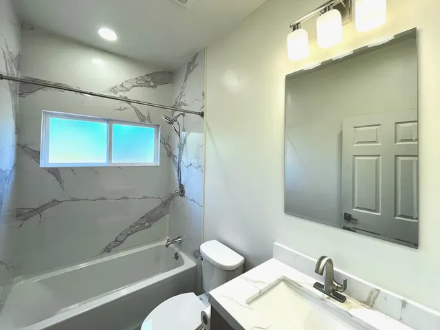 a bathroom with a granite countertop sink toilet and shower