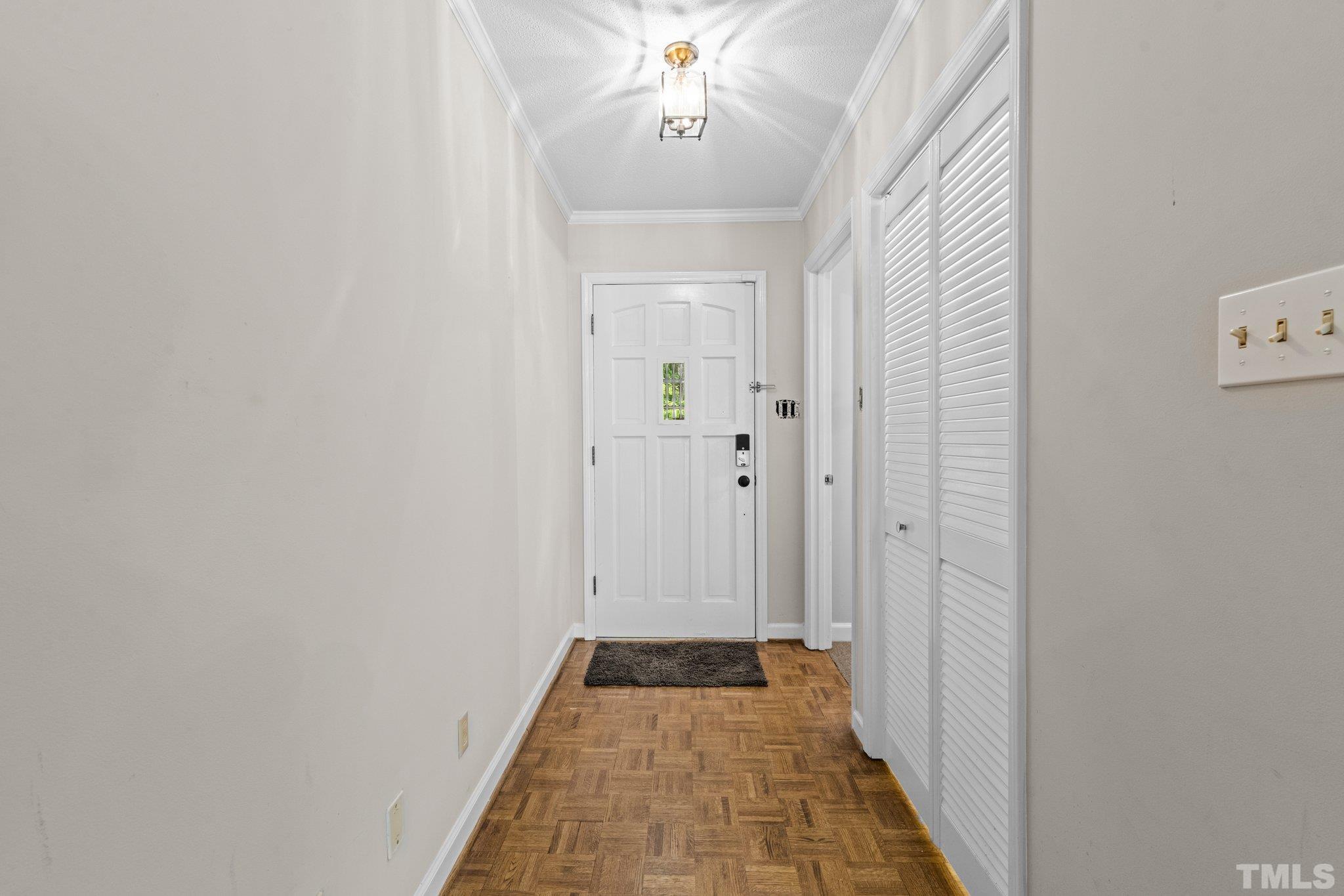 12233 Creedmoor Road Raleigh, NC 27613 - Photo 12 of 57 a view of a hallway with wooden floor and a chandelier