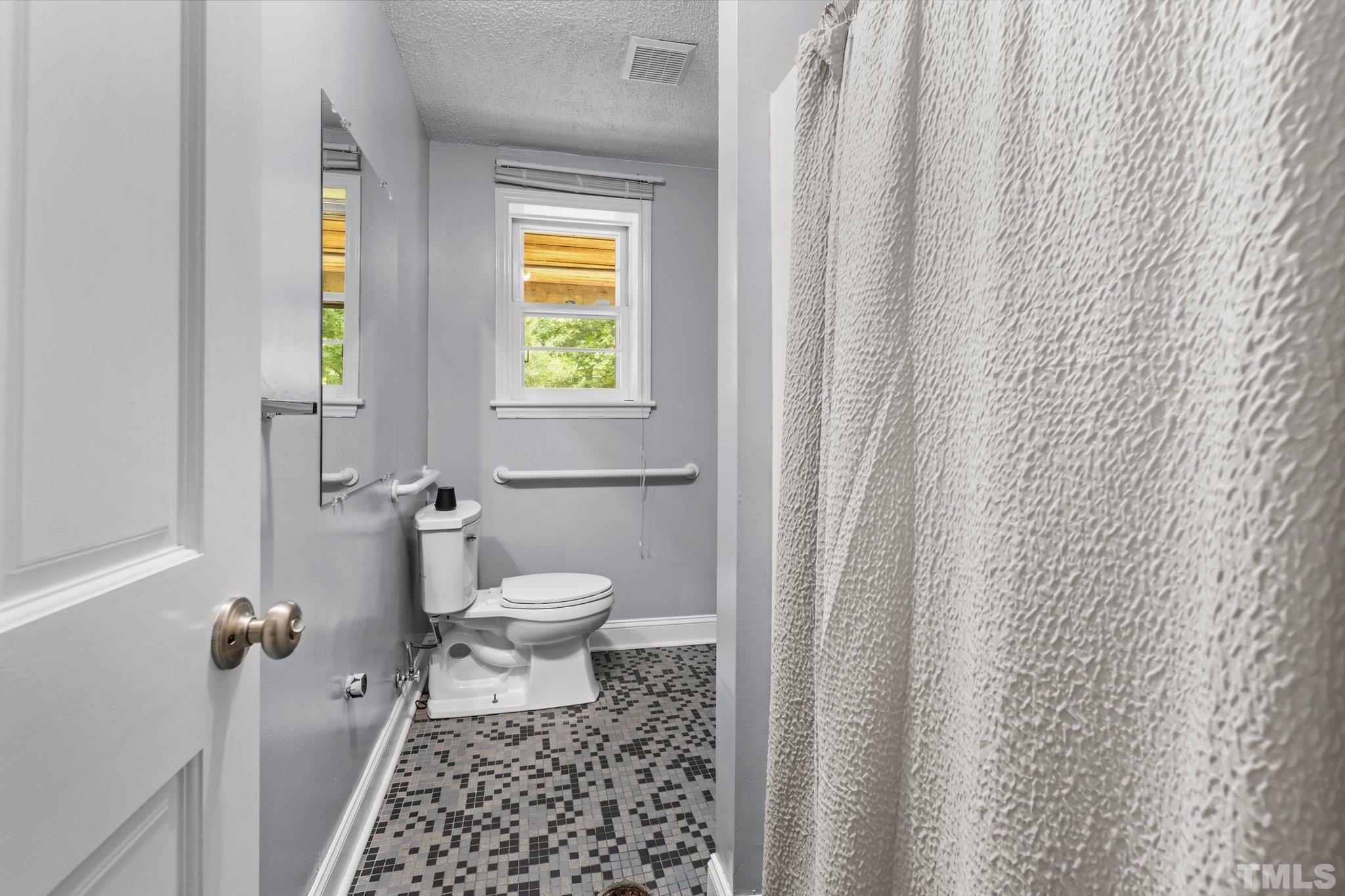 12233 Creedmoor Road Raleigh, NC 27613 - Photo 20 of 57 a bathroom with a toilet and a shower curtain